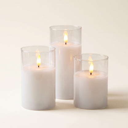 Set of three flameless LED candles in clear holders on a plain background