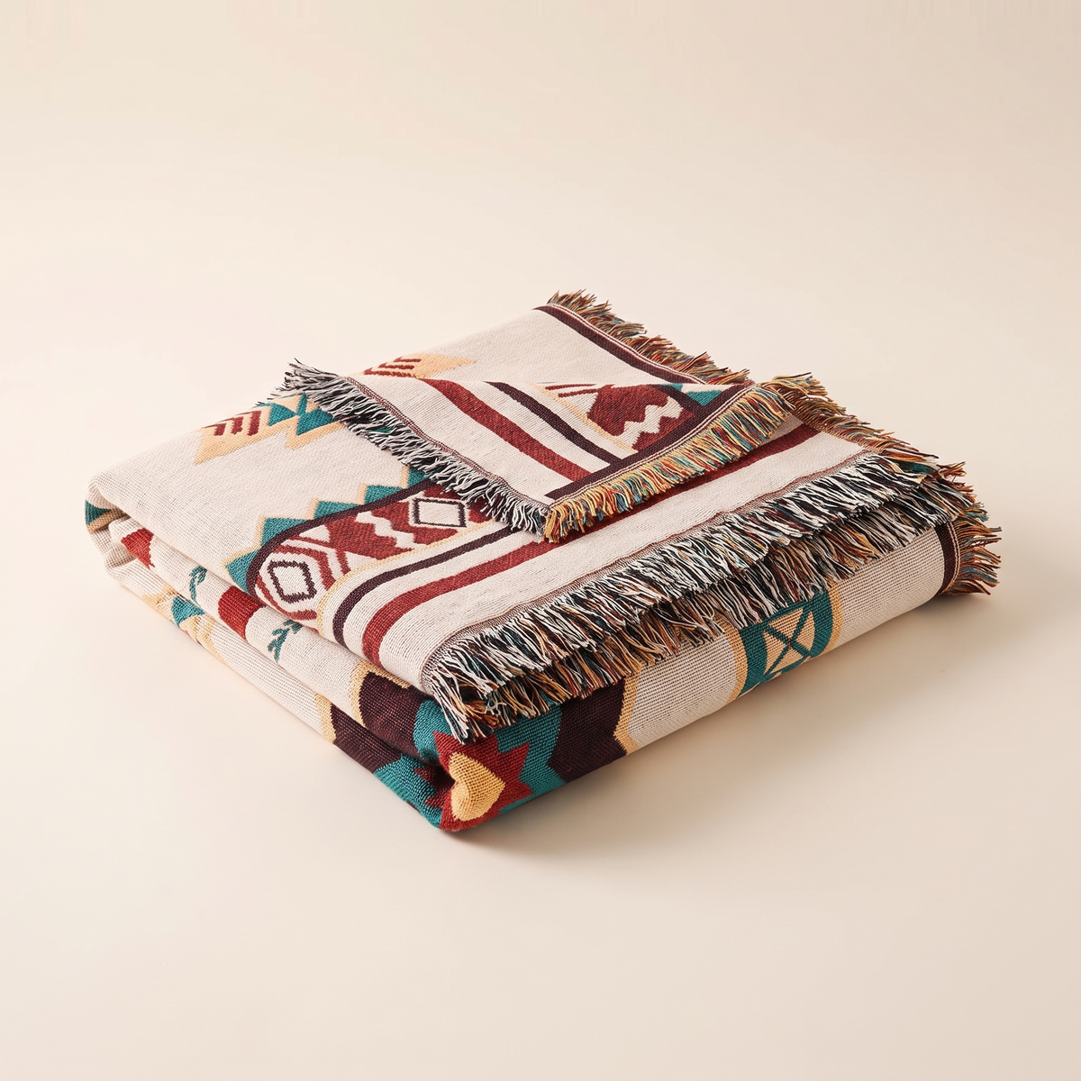 Folded boho woven throw blanket with fringe on a plain background