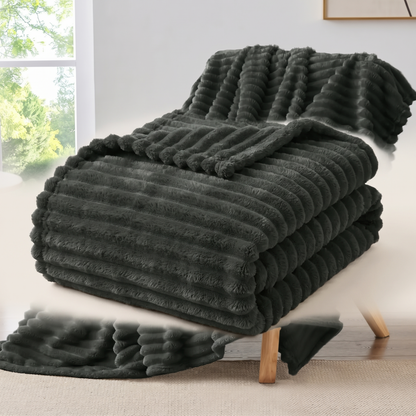 Folded ribbed fleece throw blanket on a plain background