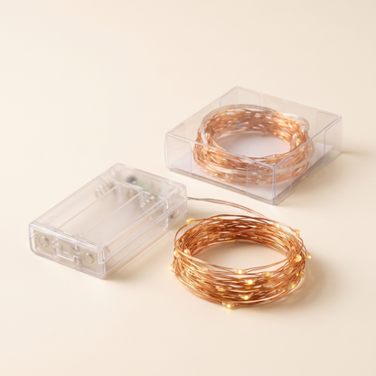 Copper wire fairy lights with battery pack on a plain background